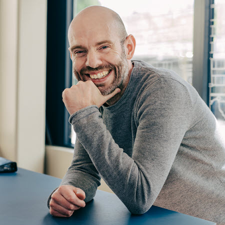 Thomas Rohberg, porträttbild. Står vid ett skrivbord.